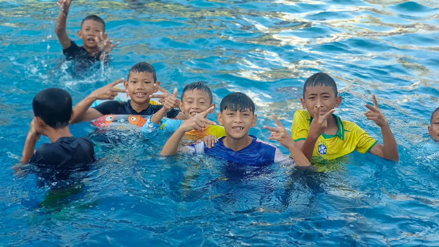 Anak-anak asuh melambaikan tangan dengan gembira di kolam renang