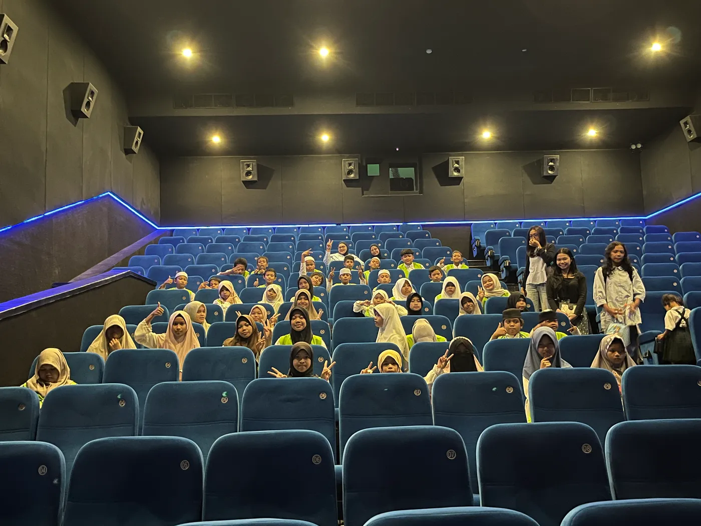 Anak-anak asuh duduk bersama di ruang bioskop