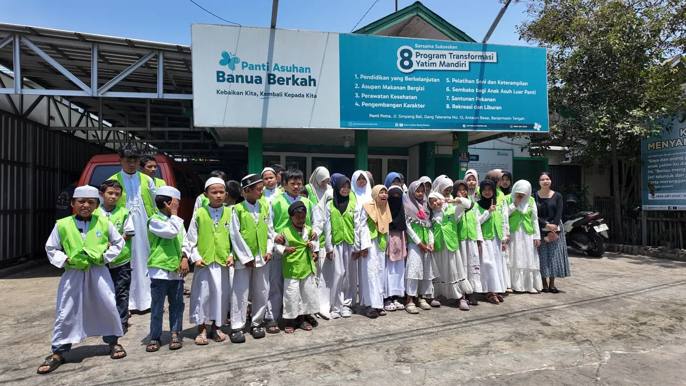 Anak-anak asuh berompi hijau berfoto bersama di depan papan nama Panti Asuhan Banua Berkah